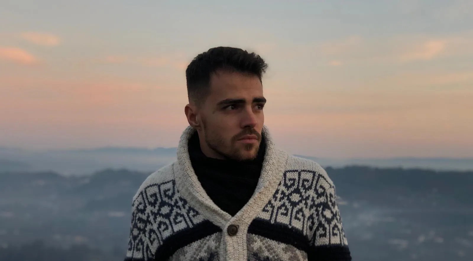 Portrait of Tiago Gil outdoors at sunset, looking to the side.